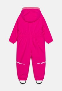 Felroze waterdichte overall met een capuchon, elastische taille, elastische manchetten en reflecterende strepen. Voorzien van zwarte voetbanden voor stabiliteit.