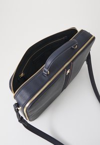 Borsa in pelle blu con zip dorata, manico superiore e tracolla removibile. L'interno è foderato con tessuto nero e presenta scomparti.