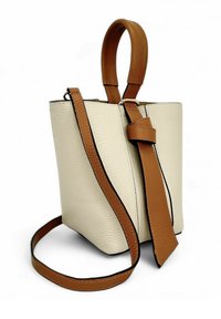 Petit sac à main en cuir beige avec une finition texturée. Il dispose d'une poignée supérieure marron et d'une bandoulière marron amovible. Design élégant avec des lignes épurées.