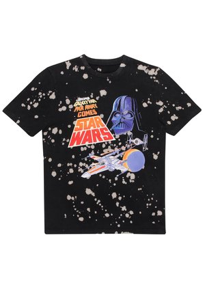 T-shirt in cotone nera con design a macchie bianche. Presenta una grafica di Darth Vader e un'astronave. Maniche corte, scollo rotondo.