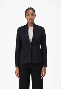 Crni sako s prilagođenim krojem, izrezanim reverima, zatvaranjem na jedno dugme i prednjim džepovima s preklopom. Nositi preko svjetlosnog rebrastog topa.