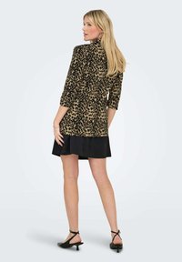 Jakna s leopard uzorkom s 3/4 rukavima, uparena s crnom A-linijom suknjom. Glatka tkanina, do koljena, s naglašenim lepršavim rubom.