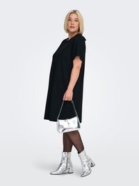 Black oversized dress with short sleeves, silver metallic ankle boots, and a matching silver handbag, worn with sheer black tights.