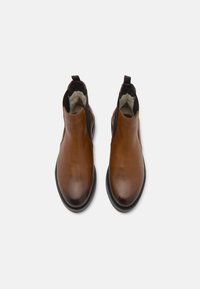 Brune lær ankle boots med elastiske sidelag, rund tå og blødt indvendigt foer. Sort gummisål for greb og holdbarhed.