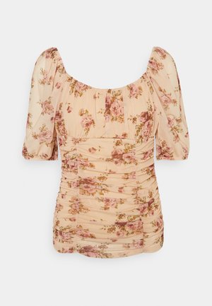 Blouse fleurie en tissu léger. Présente des manches bouffantes, des détails froncés et un fond pêche doux avec des motifs de fleurs roses.
