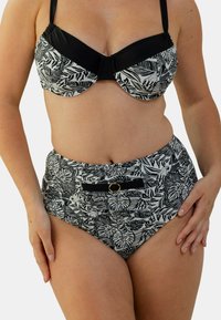 Bikini noir et blanc avec un motif de feuilles. Le haut a des bonnets moulés et des bretelles réglables ; le bas taille haute présente une bande d'accent à l'avant.