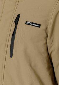 Giacca tan realizzata in un morbido tessuto testurizzato, con una tasca con zip, caratterizzata da un patch nero con la scritta "MNT dal 1997" sul davanti.