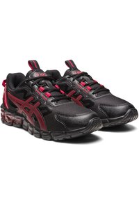 Scarpe da ginnastica nere con tomaia in rete, dettagli rossi e sovrapposizioni testurizzate. Presentano una suola ammortizzata e un design con lacci, complete di asole sul tallone.