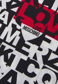 Camiseta gráfica con tipografía en blanco y negro audaz, con acentos rojos, mostrando de forma destacada "LOVE MOSCHINO" en forma de corazón.