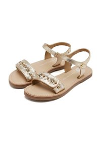 Sandalias doradas con correas de tobillo ajustables, acentos decorativos de cuentas y perlas, suela plana y un upper liso y texturizado.