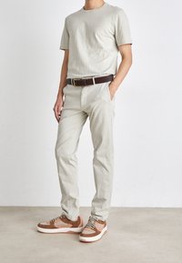 Beige t-shirt, light khaki pants with pockets, brown leather belt, and brown sneakers with light accents. Simple, casual design.