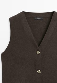 Gilet marron sans manches avec un col en V profond, comportant trois boutons dorés et un tissu doux et texturé. L'étiquette indique "Massimo Dutti."