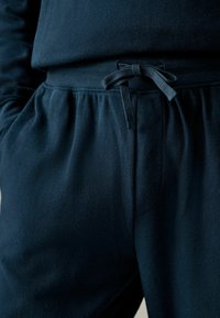 Navyblauwe loungebroek van ribstof, met een elastische tailleband met een strik aan de voorkant en zijzakken. Zachte textuur.