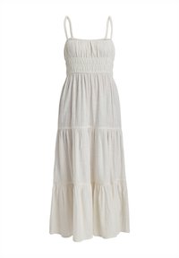 Robe maxi blanche sans manches avec un corsage smocké, une jupe à volants et un tissu texturé. Dispose de fines bretelles et d'une silhouette fluide.