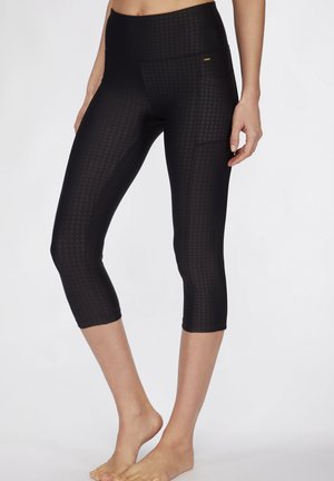 Schwarze Capri-Leggings aus Textilmaterial mit Struktur und Elasthan. Mit einem hohen Bund und einer seitlichen Tasche für Funktionalität.