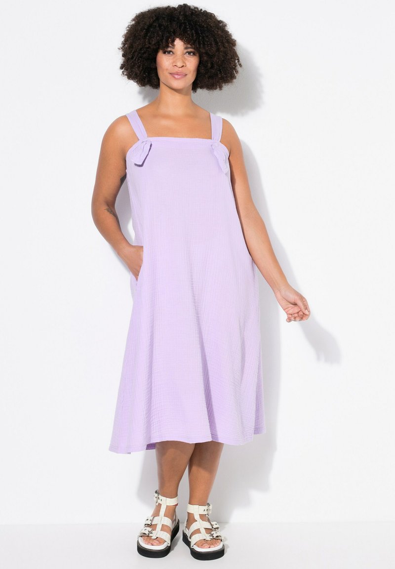 Lila Midi-Kleid mit breiten Trägern, Schleifenakzenten und seitlichen Taschen. Aus strukturiertem Stoff gefertigt, mit einer fließenden A-Linie-Silhouette.