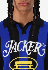 Strikket polo-skjorte med svarte og blå vertikale striper. Har en svart krage, knappeåpning, og en fremtredende "JACKER"-logo i hvitt.