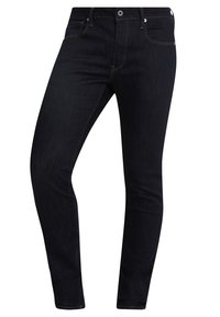 Jeans de corte ajustado en denim azul oscuro con costuras naranjas, diseño de cinco bolsillos, cremallera y cierre de botón de metal. Dobladillo en la parte inferior.