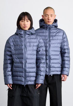 Padded jackets in a shiny light blue material. Features a hood, front zipper, and elastic drawstrings. Textured with horizontal quilted sections.