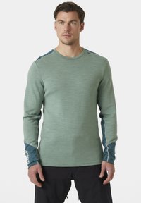 Světle zelená dlouhá košile s dlouhým rukávem, texturovaná látka, kontrastní modré akcenty na rukávech, kulatý výstřih, přiléhavý design, bez grafiky nebo vzorů.