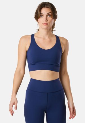 Reggiseno sportivo blu navy con scollatura a giro e spalline larghe, realizzato in tessuto elastico, abbinato a leggins aderenti a vita alta.