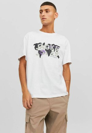 Camiseta blanca de algodón con un diseño gráfico de un mapa mundial que incluye "JACK & JONES" en colores oscuros y claros, combinada con pantalones cargo beige.