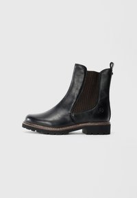 Bottine Chelsea en cuir noir avec panneau élastique latéral marron, semelle épaisse et tirant à l'arrière, présentée de profil sur un fond blanc.