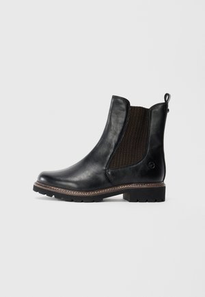 Bottine Chelsea en cuir noir avec panneau élastique latéral marron, semelle épaisse et tirant à l'arrière, présentée de profil sur un fond blanc.