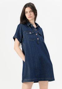 Denim shirt jurk in donkerblauw met korte mouwen, knopen aan de voorkant, twee borstzakken en zijzakken. Heeft een comfortabele pasvorm en een afgewerkte zoom.