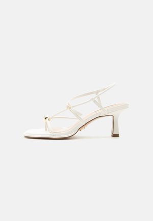 Sandalo bianco con cinturini, tacco a blocco di altezza media e piccolo dettaglio con fibbia dorata sulla fascia anteriore.