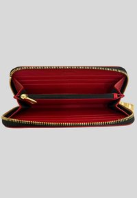 Portafoglio zip-around nero e rosso con zip dorata, multiple fessure per carte e un compartimento centrale con zip per le monete all'interno.