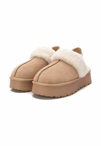 Scarpe slip-on in suede color sabbia con un morbido colletto in pelliccia cremosa, dotate di una suola piatta spessa e testurizzata e dettagli laterali cuciti.
