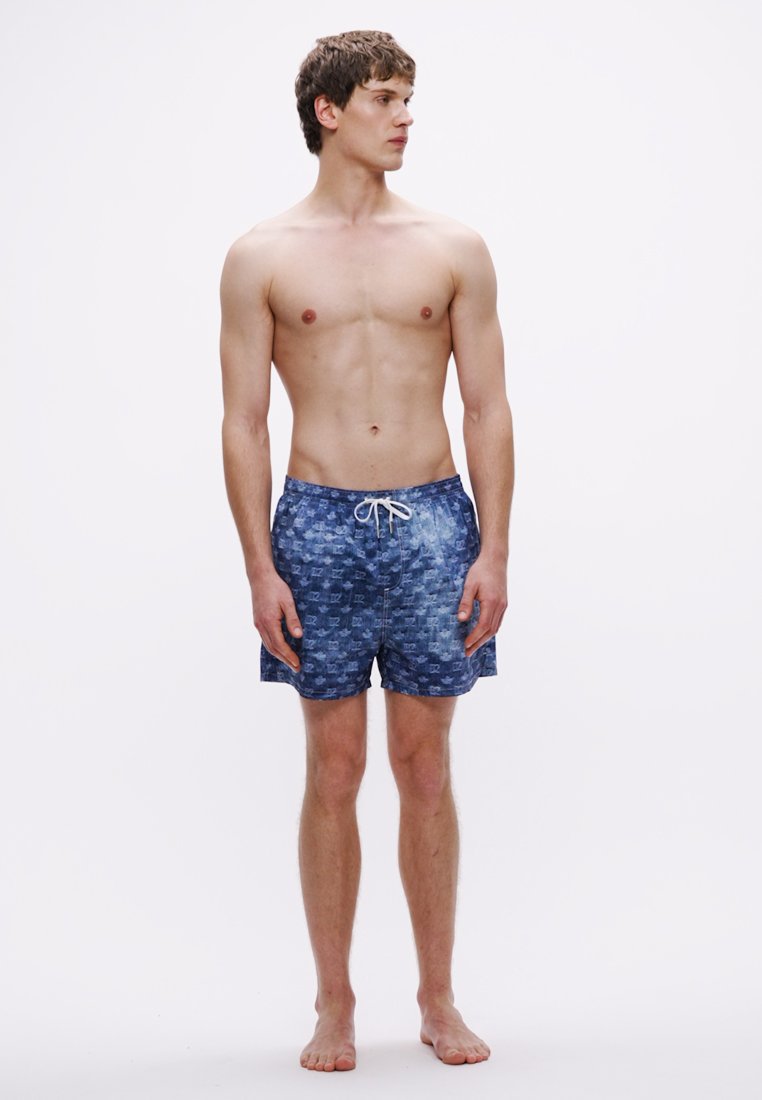 Shorts de bain bleus avec un motif pixélisé, une taille à cordon et une coupe au-dessus du genou. Le tissu semble léger et à séchage rapide.