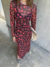Langermet kjole med kirsebærmønster i rød og svart, med en tettsittende silhuett og gjennomsiktig materiale, kombinert med en beige clutch og høyhælte sko med leopardmønster.