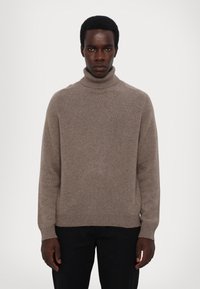 Beige Rollkragenpullover aus weichem Strick mit gerippten Bündchen und Saum, entspanntem Schnitt und minimalistischem Design.