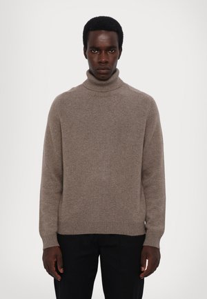 Pull à col roulé beige en tricot doux, avec des poignets et un ourlet côtelés, à coupe décontractée et design minimaliste.