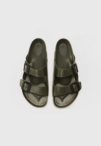 Olive green sandals made of plastic with two wide straps. Features a textured footbed and black buckle hardware for adjustable fit.