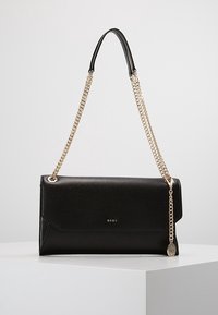 Pochette in pelle nera con design a piegatura, tracolla a catena dorata e logo di marca. Texture liscia e stile minimalista.