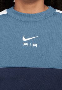 Niebieski i granatowy sweatshirt z okrągłym dekoltem, wykonany z mieszanki bawełny, z białym logo Nike i napisem "AIR" na klatce piersiowej, o delikatnej teksturze dzianiny.