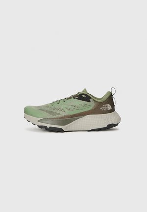 Chaussure de trail de couleur vert clair avec une tige texturée, des accents noirs et une semelle rembourrée. Dispose d'une languette de tirage et d'un design à motifs.
