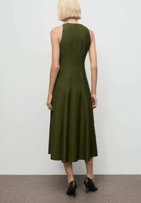 Vestido midi sin mangas en verde oliva, hecho de una tela suave, con un cuerpo ajustado y falda acampanada. La parte trasera cuenta con un cierre de cremallera simple.