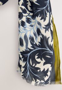 Écharpe à motif floral aux couleurs bleu marine, bleu clair et crème avec des bords à franges. Un côté est uni vert olive. Texture de tissu doux.