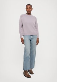 Light purple sweater with ribbed cuffs and hem, paired with high-waisted blue jeans and brown ankle boots. Casual fit with minimalistic design.