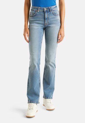 Lichtblauwe, uitlopende jeans van denim, met vijf zakken en contrasterende stiksels, gecombineerd met witte sneakers.