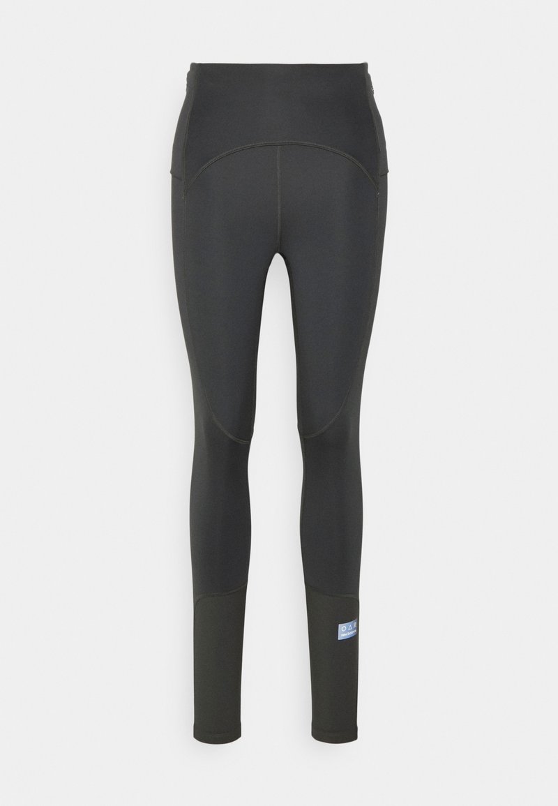 Collants de sport noirs taille haute avec des panneaux contrastants sur le bas des jambes et une petite étiquette bleue sur le mollet droit.