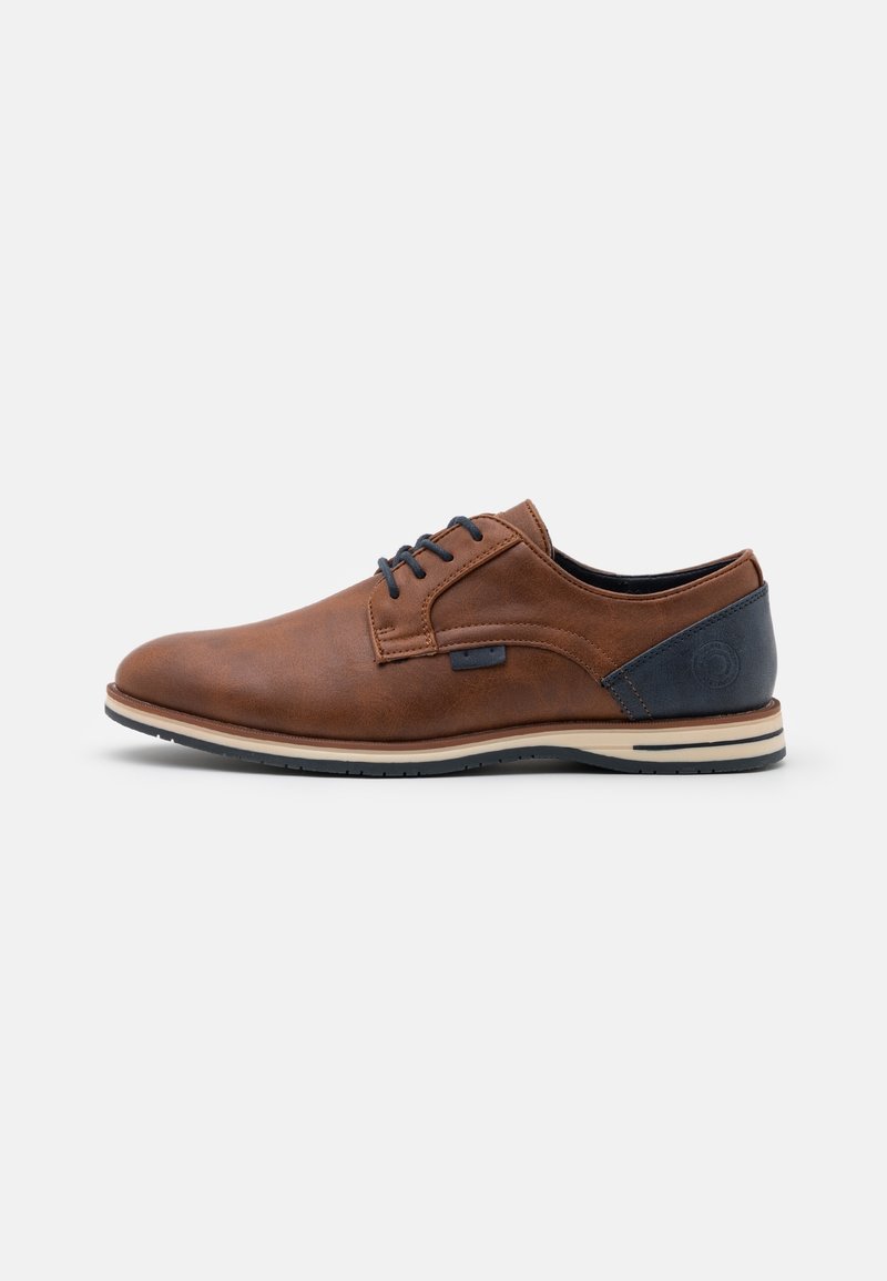 Chaussure habillée pour homme en cuir marron à lacets avec patch noir au talon et semelle claire, vue de côté sur fond blanc.