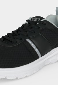 Baskets Jack & Jones noir et blanc avec lacets noirs, tige en mesh respirant, col rembourré et semelle blanche texturée.