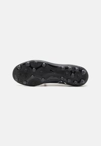 Suela de botas de fútbol negras con tacos moldeados y una superficie texturizada para tracción. Incluye el logotipo de la marca visible y elementos de diseño moldeados.