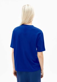 T-shirt en coton bleu avec une coupe décontractée, des manches courtes et un col rond ; design uni sans motifs ni accents visibles.