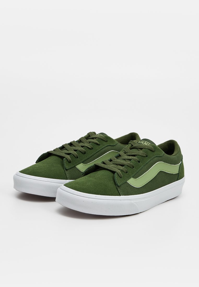 Par de zapatillas bajas de color verde oliva con suelas de goma blancas y franjas laterales verde claro, exhibidas sobre un fondo claro y sencillo.